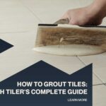 Hand applying grout between floor tiles during a tile installation project.
